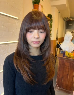 butterfly haircut with face framing bangs on ash golden brown by McKenzie at ESHK Toronto hair salon Dundas West